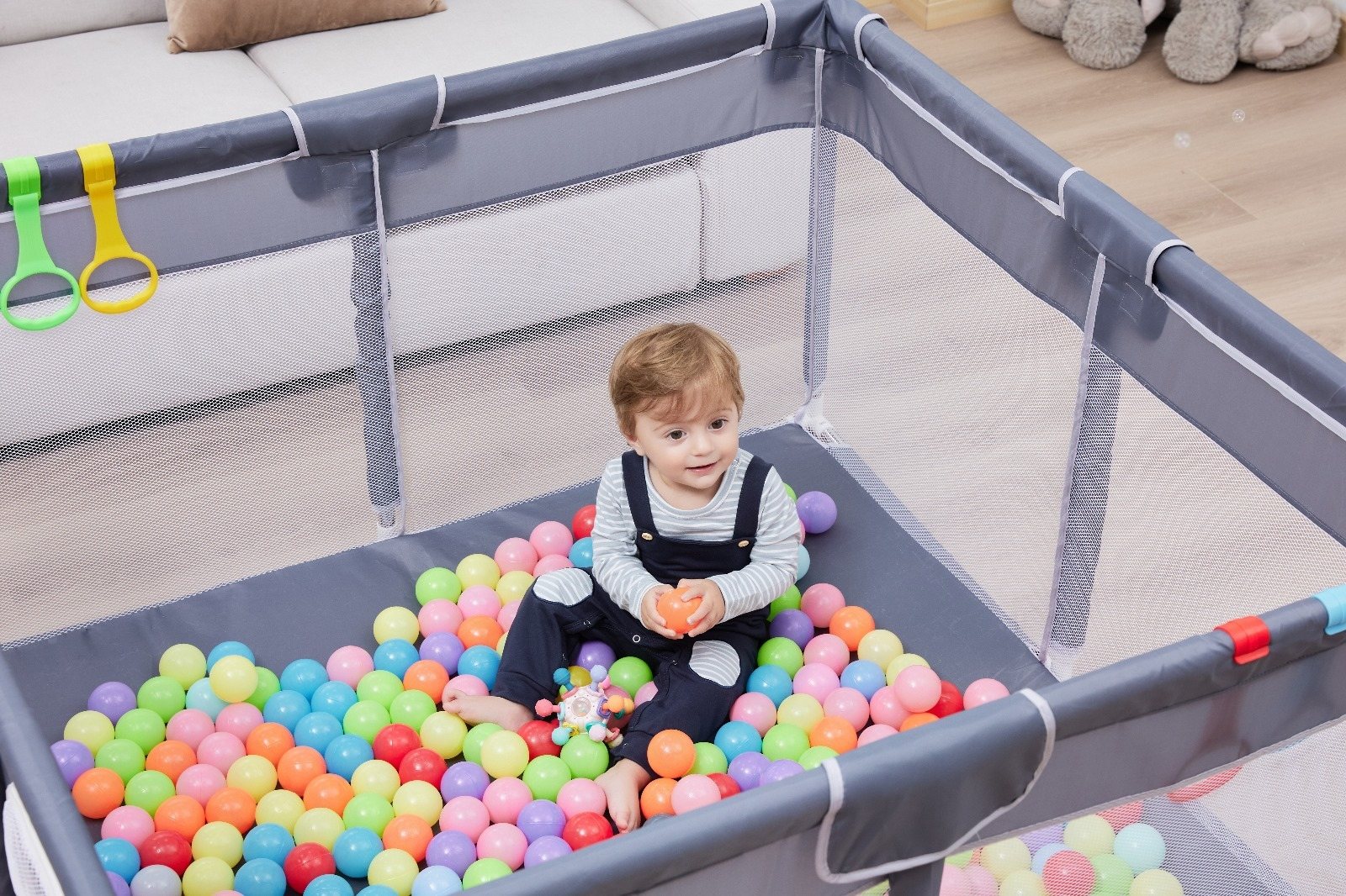 Baby playing with colorful balls inside an Orian Babies playpen